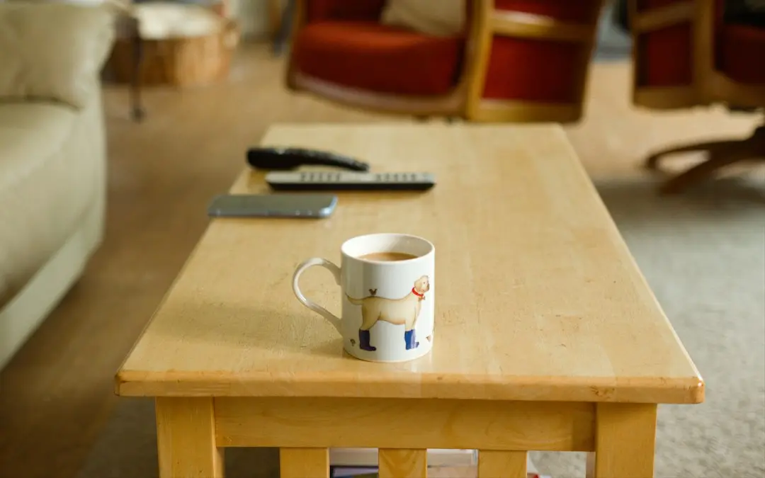 A smartphone and two TV remotes beside a mug on a wooden coffee table, ready to install an app for Nexus4kTV