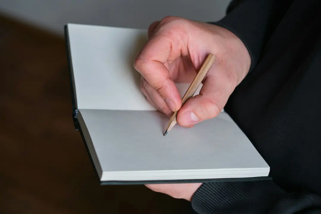 A hand with a pencil writes in a blank notebook, comparing IPTV providers such as Nexus4kTV