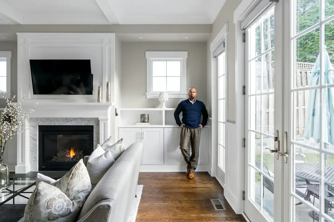 A man stands in a bright living room with a wall-mounted TV above the fireplace, where Nexus4kTV can be set up